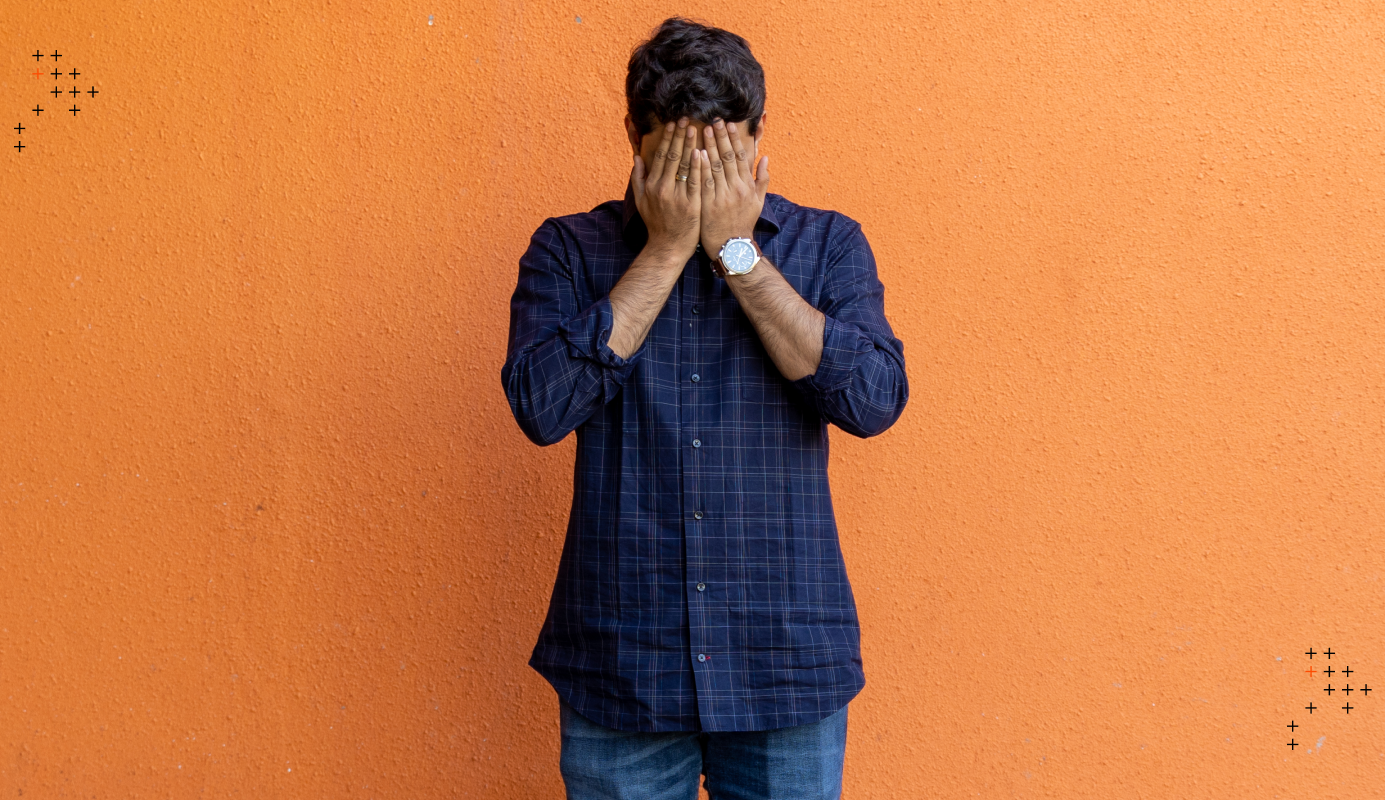 An employee covering his face with his hands as a sign of feeling dejected