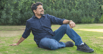 A person sitting peacefully on a patch of grass. 